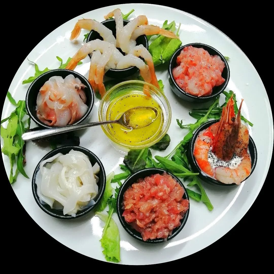 Crudités di mare con carpacci e salmone affumicato su piatto nero