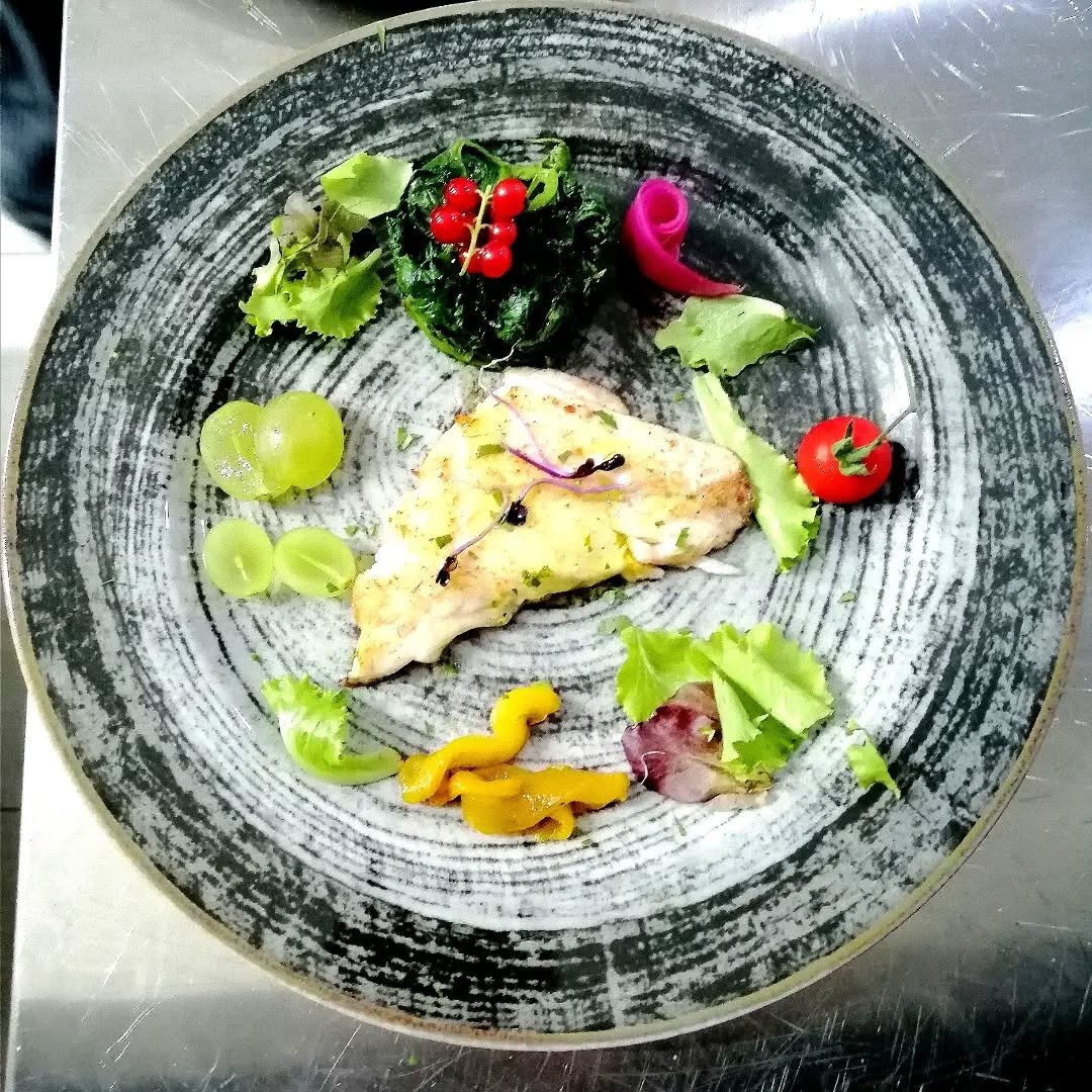 Filetto di pesce su pietra grigia con verdure marinate