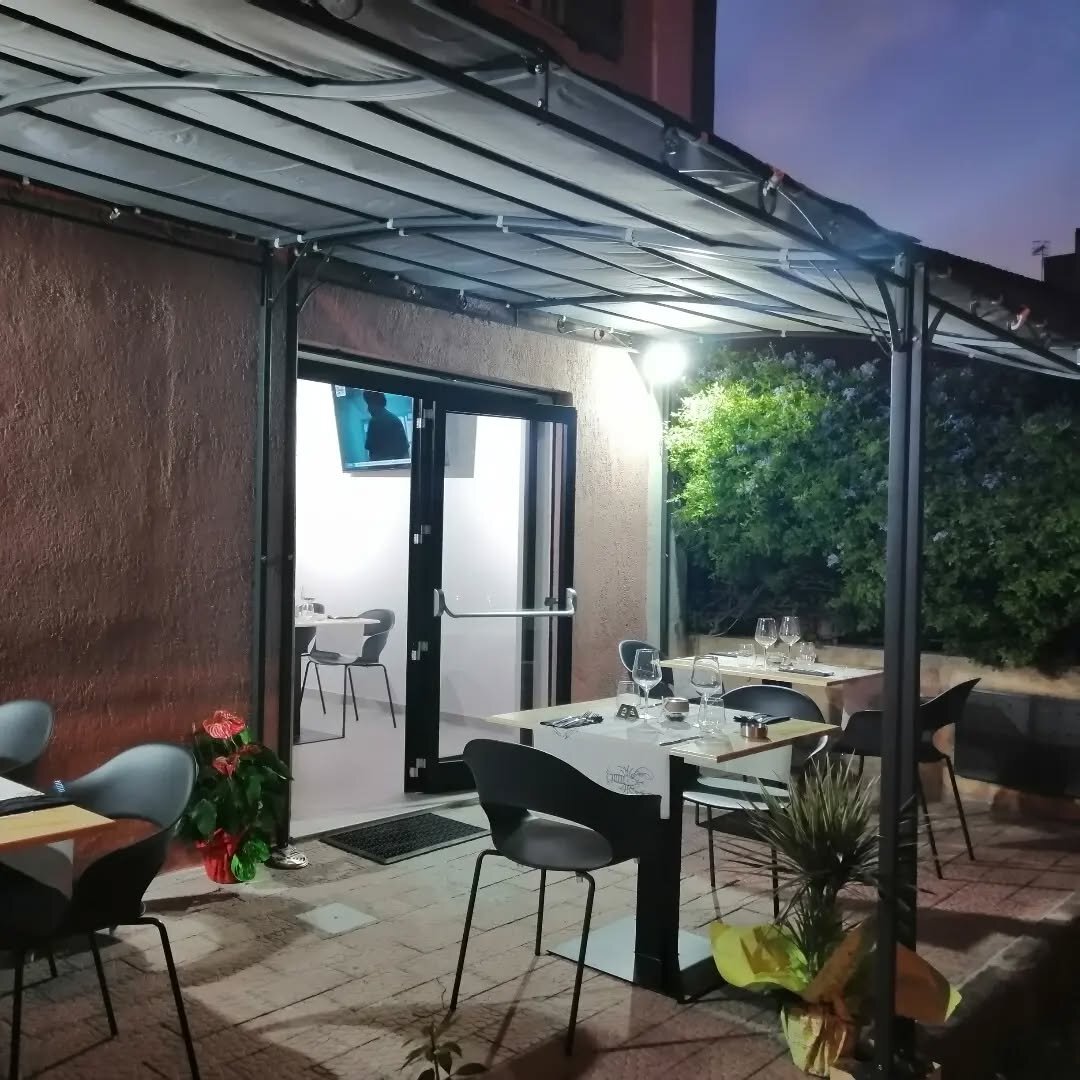 Vista lunga della terrazza Serrago di sera, sotto il pergolato illuminato